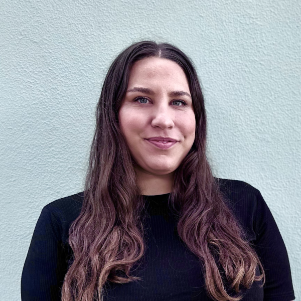 Headshot of clinical psychologist Laura Nolan wearing a black top, standing against a light textured wall.