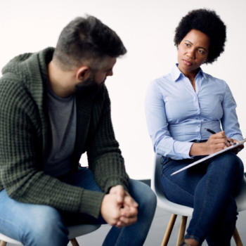 Adult in therapy session with a psychologist taking notes